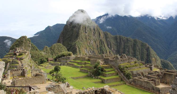 Vue panoramique du Machu Picchu avec des nuages autour des sommets.
