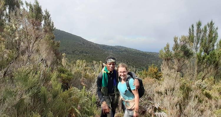 Zwei Personen wandern und posieren auf einem Wanderweg, umgeben von buschigem Gelände.
