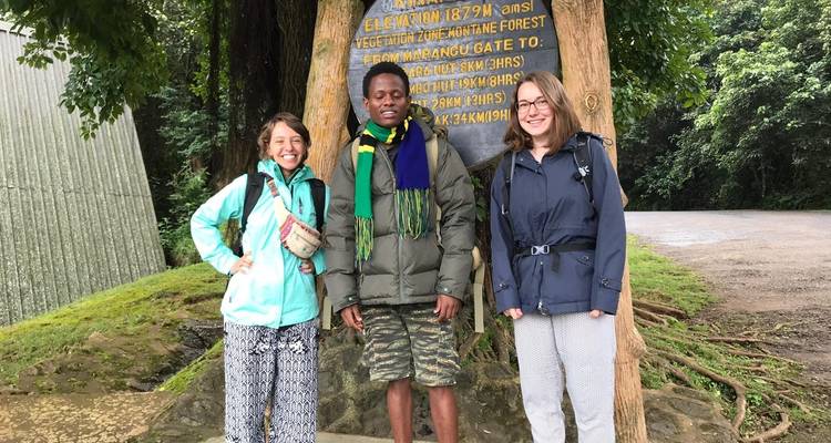 Drei Personen posieren vor einem Schild an einem Wander- oder Naturstandort.