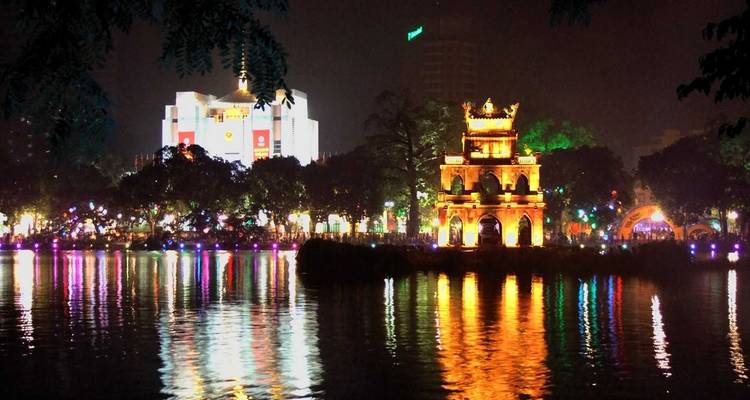 Temple brillamment éclairé avec reflet dans le lac la nuit.