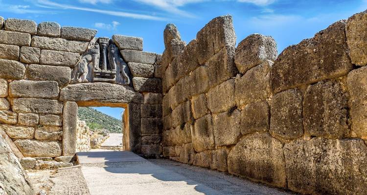 The Lion Gate at the ancient city of Mycenae, a well-preserved archaeological site with large stone walls and a clear blue sky.