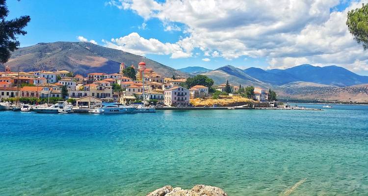Scenic coastal town with colorful buildings by the sea and mountains in the background.