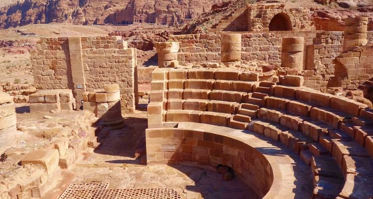 Antike Amphitheater-Ruinen umgeben von Wüstenlandschaft.