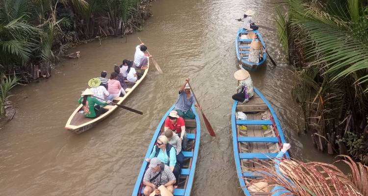 Personas remando en botes por un río rodeado de árboles.