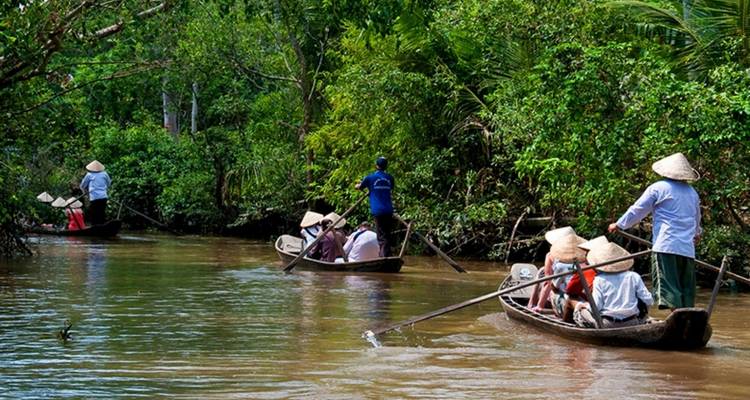 Turistas en botes tradicionales en un río rodeado de exuberante vegetación.
