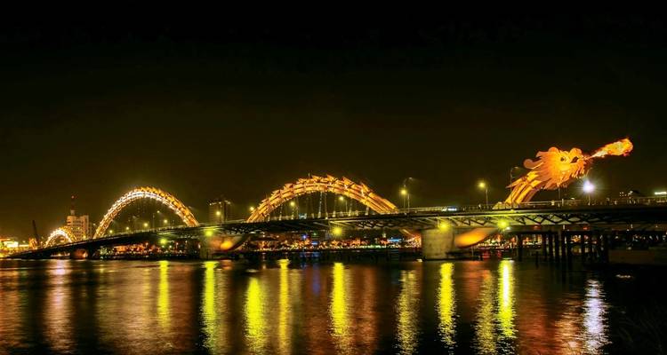 Dragon Bridge illuminated at night over a river.