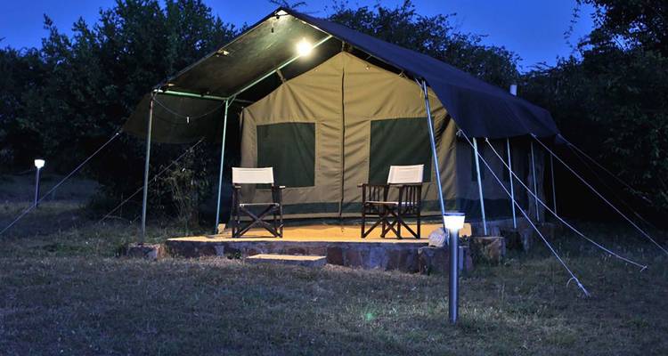Een tent verlicht in de nacht in een kampeeromgeving.