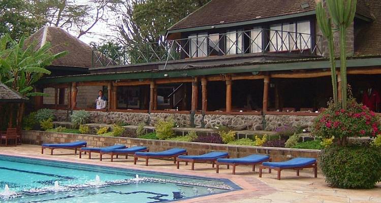 Lodge with a pool and lush greenery surrounding.