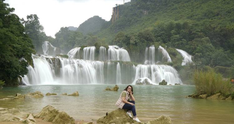 Une femme qui pose devant une grande cascade.