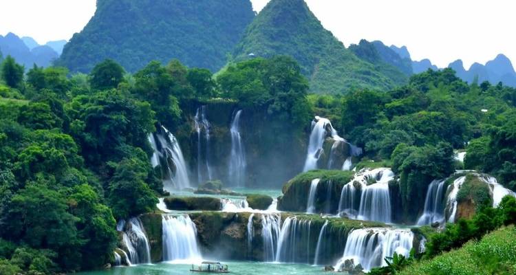 Une belle cascade au milieu de collines vertes et d'arbres.