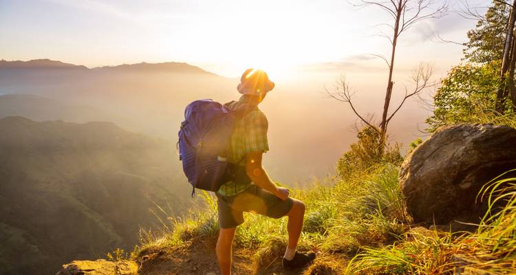 Person standing on a cliff during sunset