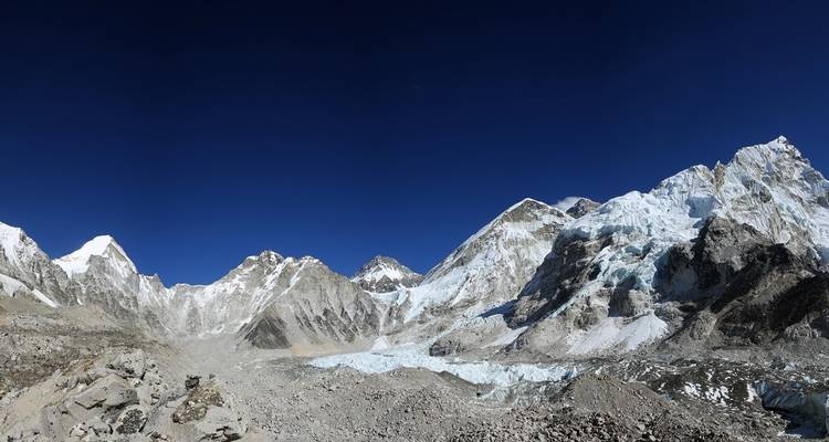 Groothoekopname van een rotsachtig berglandschap met besneeuwde toppen.