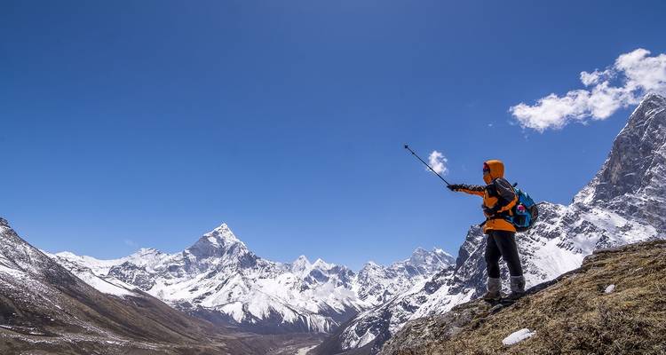 Ein Wanderer mit Trekkingstöcken, der auf schneebedeckte Berge blickt.