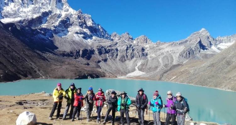 Eine Gruppe von Personen an einem See mit Bergen im Hintergrund.