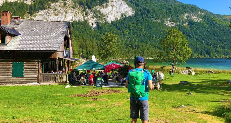 Voyageur près d'un lac avec zone de restauration au bord de l'eau et montagnes.