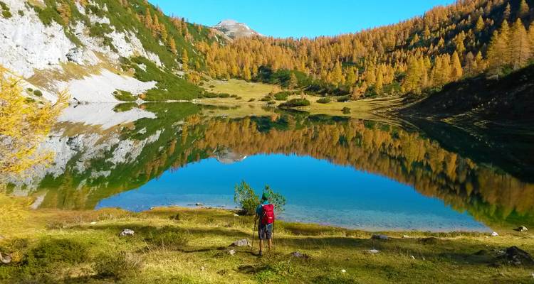 I notice you asked me to translate from English to French, but the text you provided appears to already be in English. Here's the French translation:
"Randonneur solitaire au bord d'un lac miroir avec des arbres aux couleurs d'automne et des montagnes."