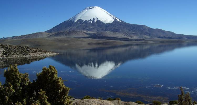 Ein großer schneebedeckter Berg, der sich in einem unberührten See spiegelt.