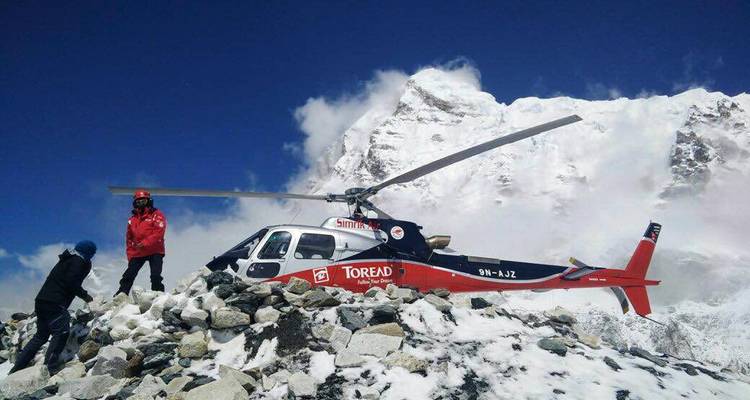 Helicopter on a snowy mountain with people.