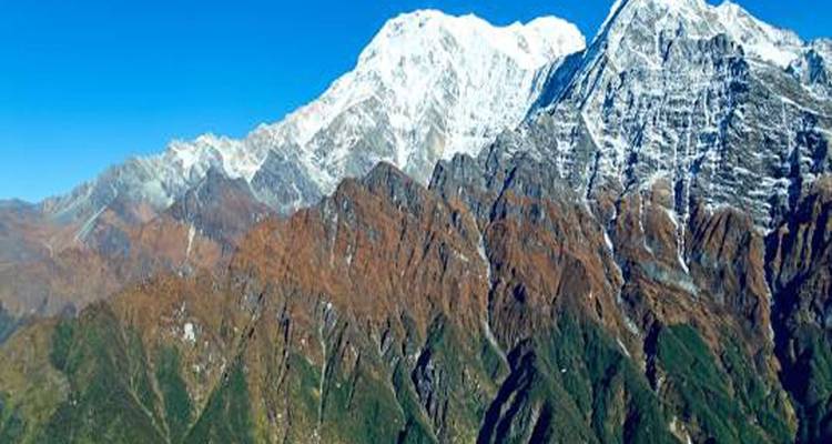 Schneebedeckte Bergkette unter klarem blauen Himmel mit zerklüftetem Gelände.