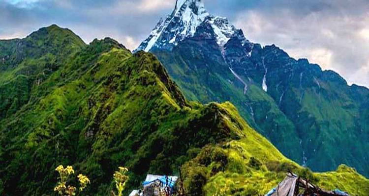 Grüne Berge mit einem schneebedeckten Gipfel und einer kleinen Siedlung darunter.