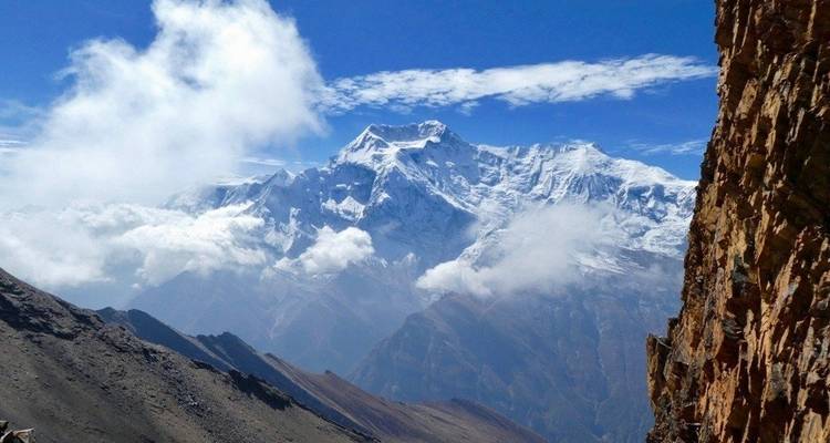 Dramatische schneebedeckte Gipfel mit Wolken über einer zerklüfteten Landschaft.