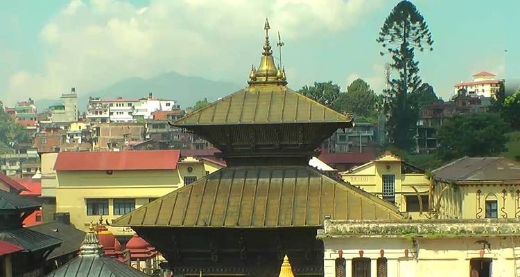 Temple avec bâtiments environnants et collines en arrière-plan.