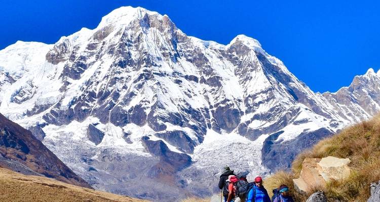 Hikers near the base of snow-covered mountains.