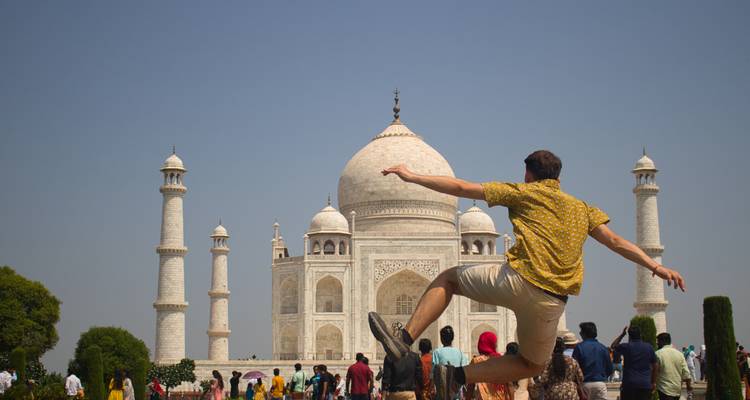 Persoon die springt voor de Taj Mahal met een menigte.