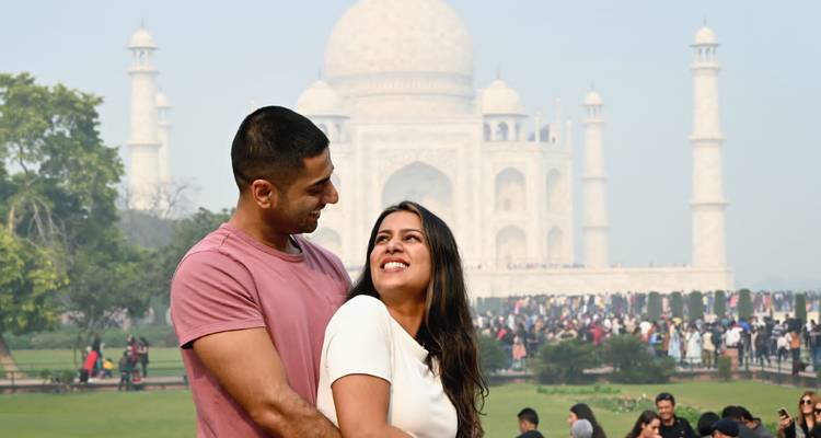 Stel poseert voor de Taj Mahal met een wazige lucht.