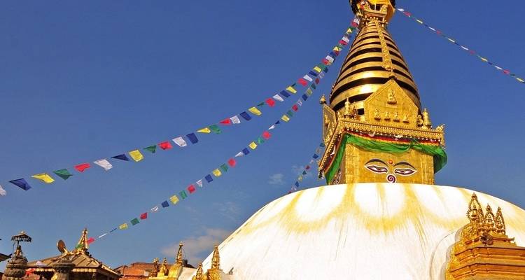 Golden stupa with prayer flags against the sky.