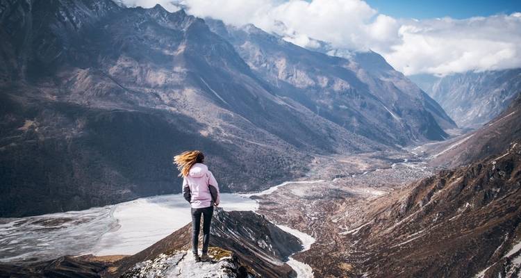 Person standing on mountain overlooking a valley.