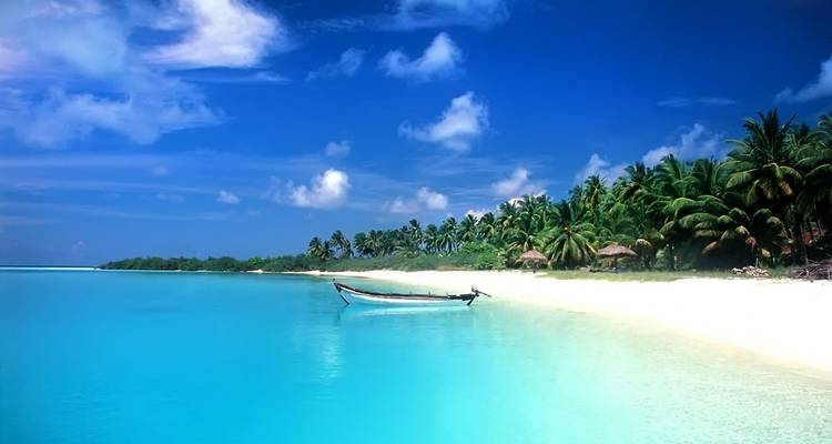 Strand met helder blauw water en een eenzame boot.