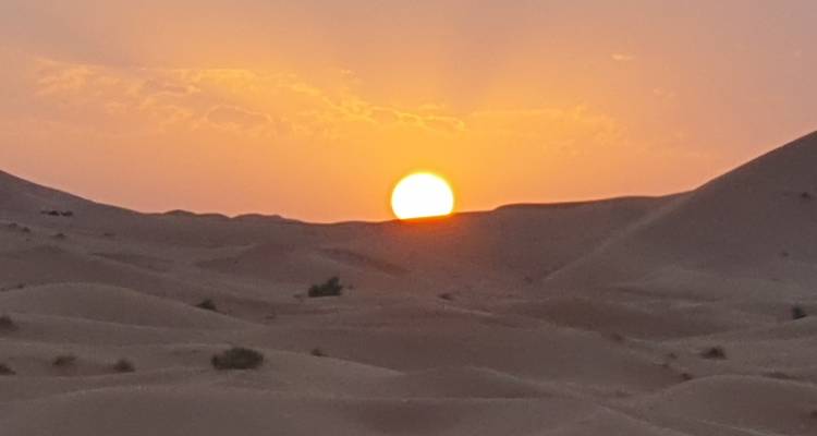 Atardecer sobre dunas desérticas distantes.