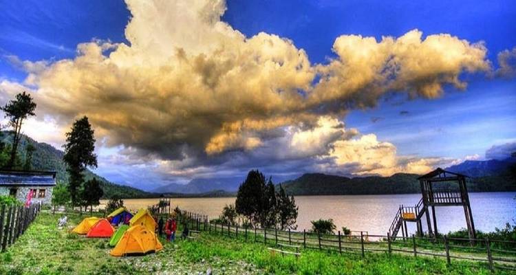 Kampeerscène bij een groot meer onder dramatische wolkenformaties.