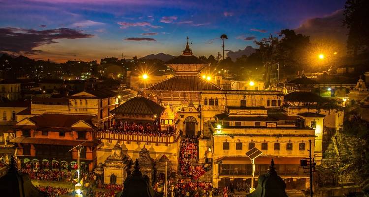 Pashupatinath Temple complex glowing at dusk with city lights.