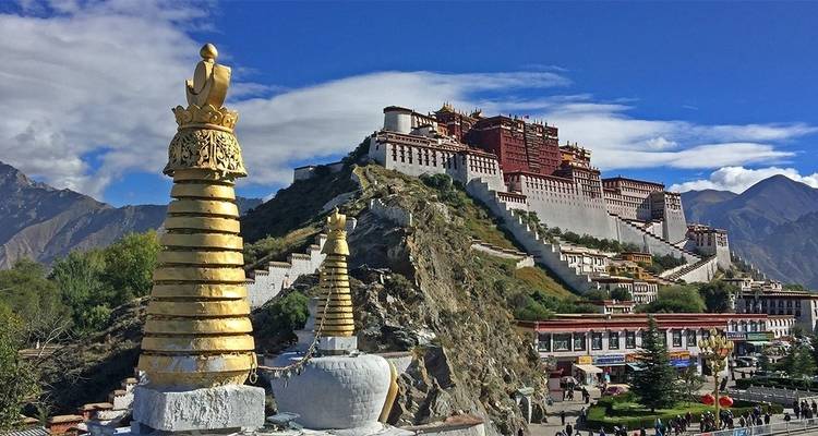 Potala Palace in Lhasa with vibrant blue sky and statues.