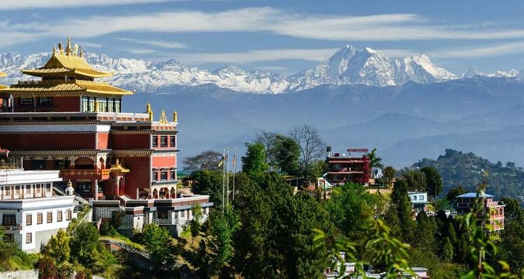Buntes Kloster mit schneebedeckten Bergen im Hintergrund.