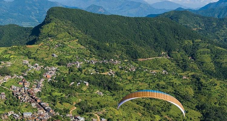 Paragleiter über einer üppigen, grünen Landschaft.