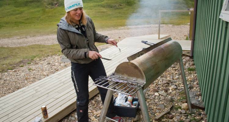 Person grilling in a scenic outdoor setting with a smoker.