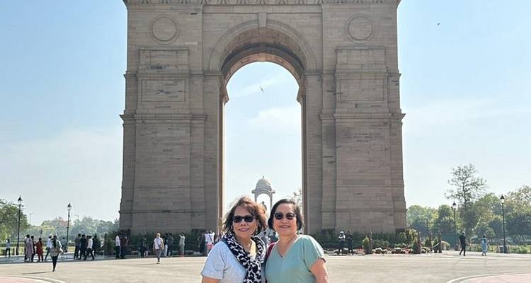 Dos mujeres posando frente al monumento de la Puerta de la India en un día soleado y despejado.