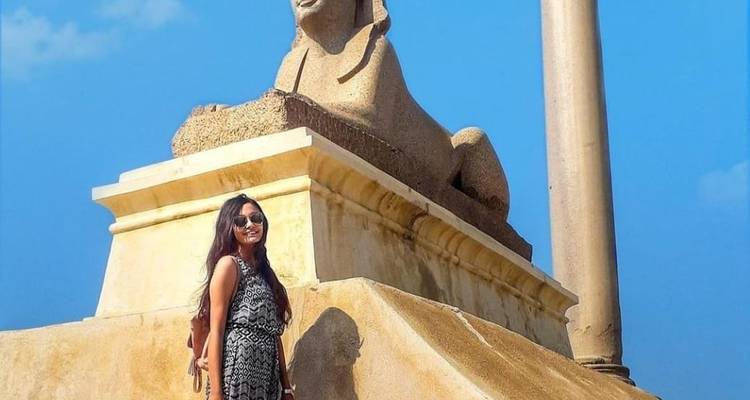Woman posing next to a sphinx statue in Alexandria.