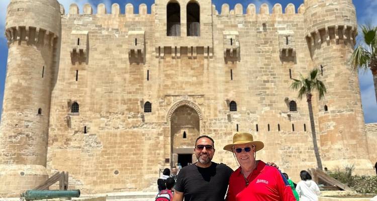 Two men posing in front of a historic fortress.