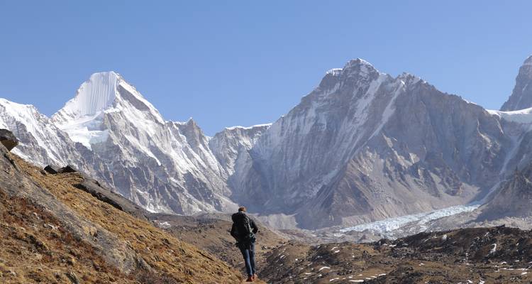 Personne debout devant l'Himalaya sous un ciel bleu éclatant.