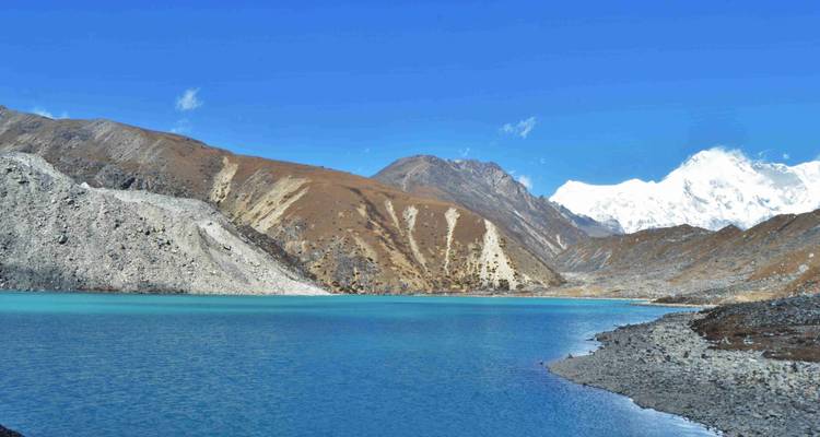 Lago de montaña con agua azul cristalina rodeado de terreno rocoso.