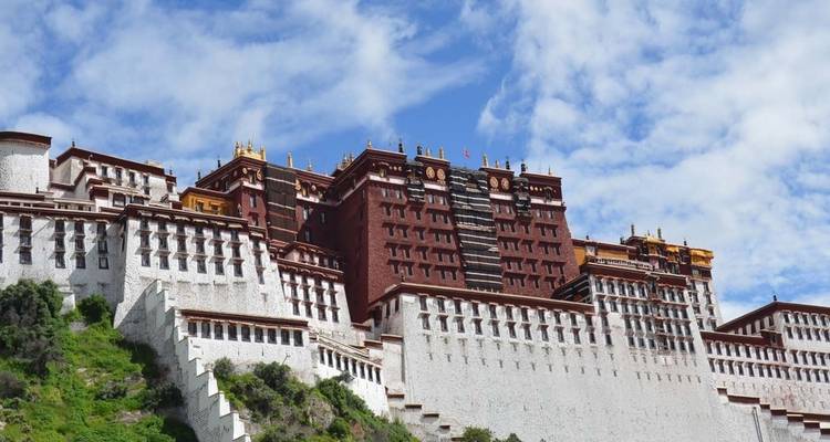 A grand palace structure against a bright blue sky, sitting on a hill.