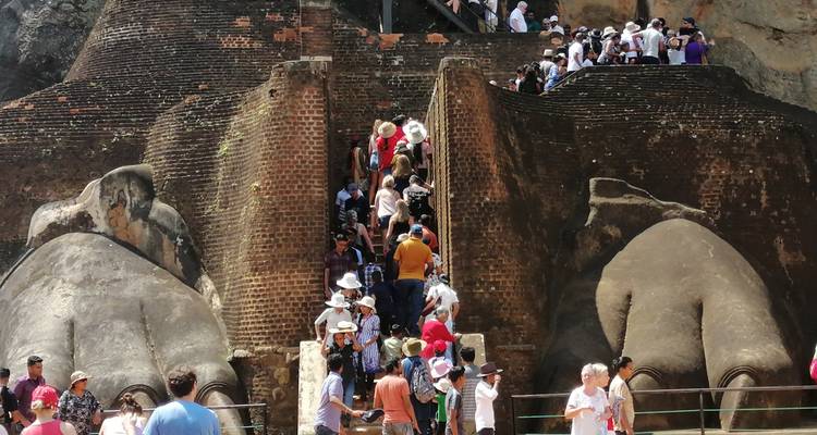 Tourists climbing steps at Sigiriya Lion's Rock entrance.