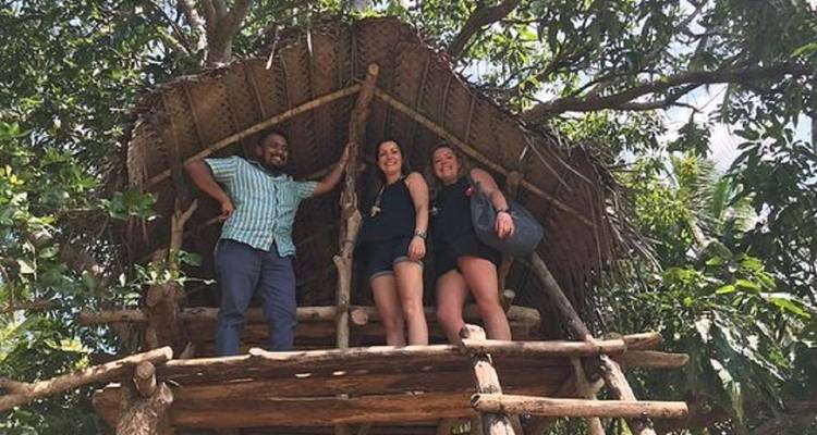 Drei Menschen in einer rustikalen Baumhaus-Umgebung, umgeben von dichtem Laub.