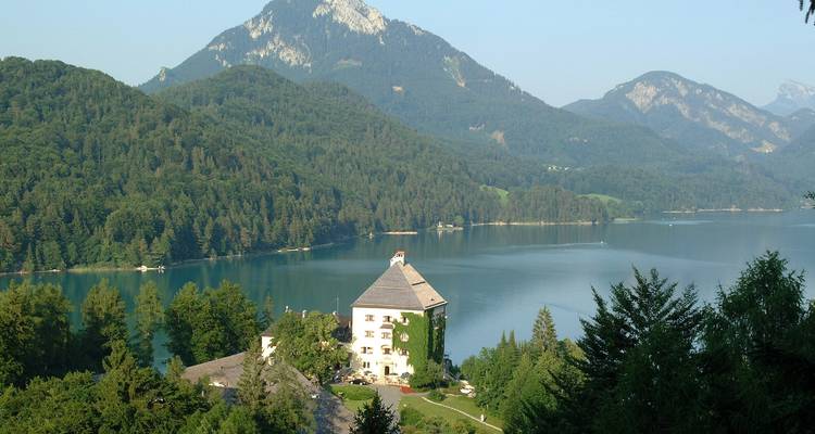 Vista panorámica de un lago con bosque denso y montañas.