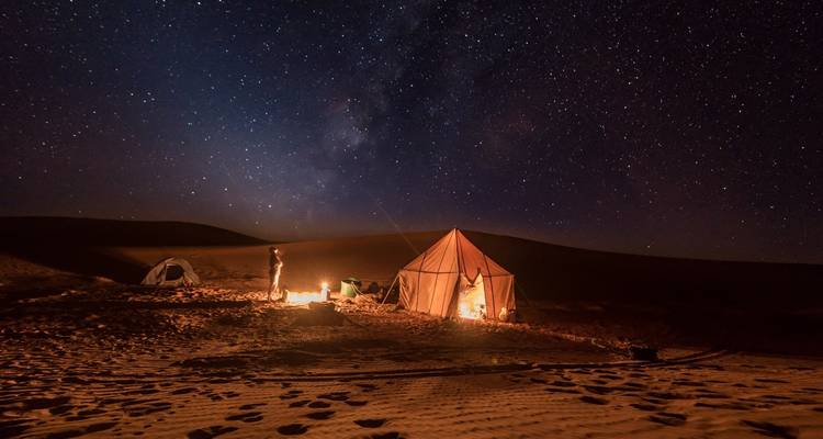 Woestijnkamp onder een sterrenhemel.