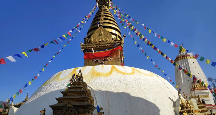 Swayambhunath Stupa with prayer flags on a sunny day.